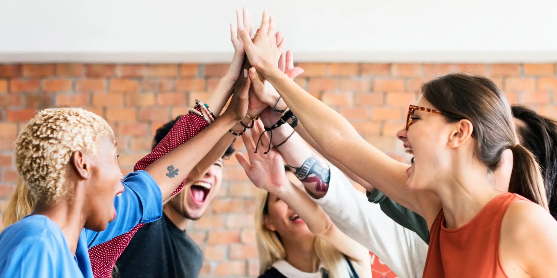 Group of people enthusiastically giving a high-five indoors.