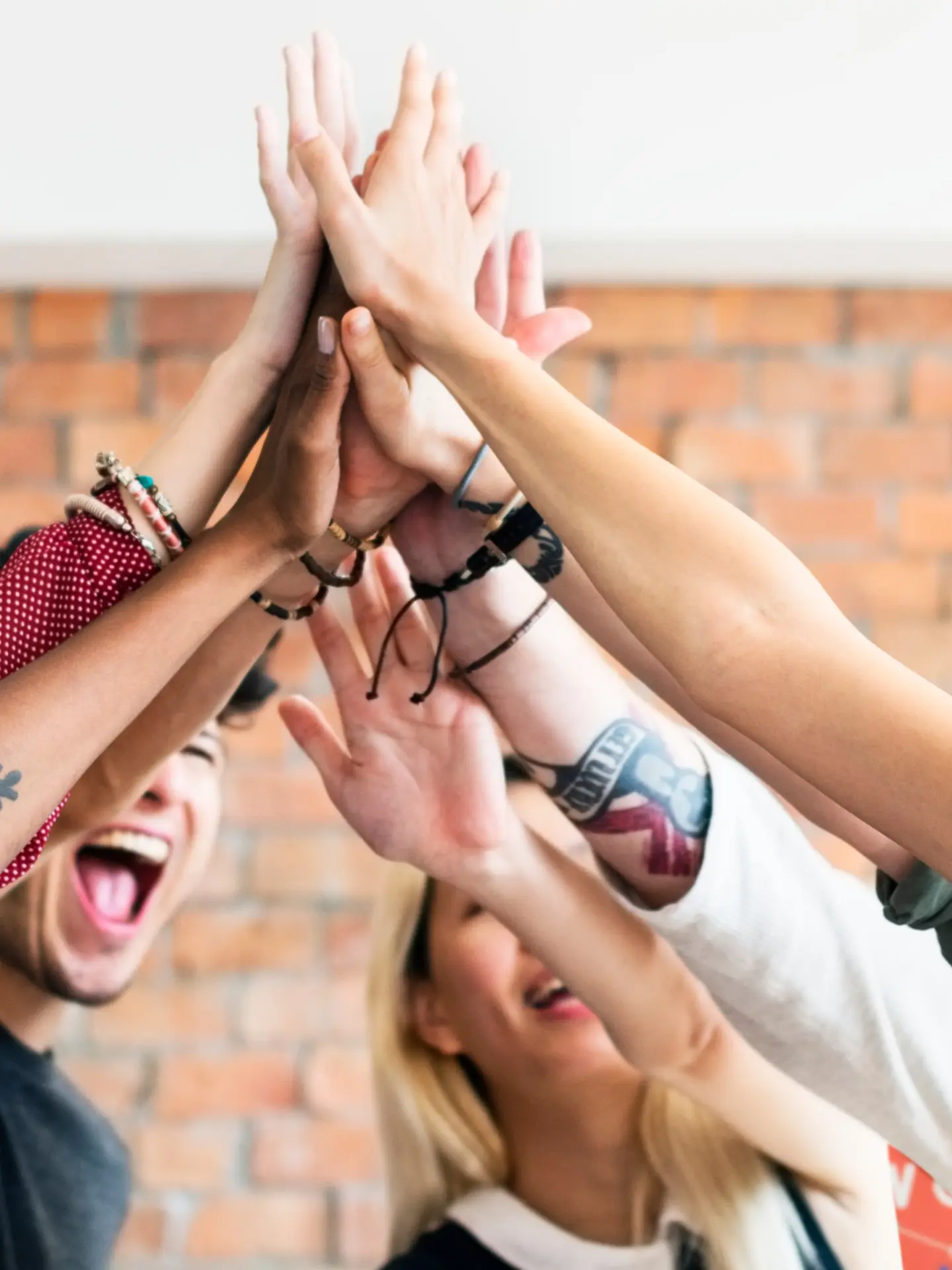 Group of diverse people giving high-fives, smiling enthusiastically.
