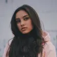 Young woman with long hair, wearing a pink hoodie, looking at the camera.