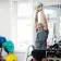 Man lifting a kettlebell in a gym, surrounded by weights and mirrors.
