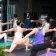 Women in yoga poses at an outdoor class, wearing colorful workout attire.