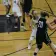 Basketball game, player in black jersey holds ball, player in white defends on a wooden court.