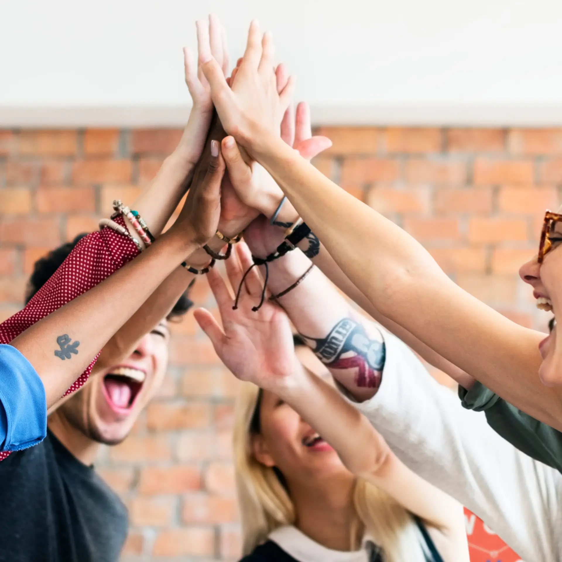 Group of people enthusiastically giving a high-five indoors.